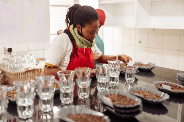 African American female worker placing notes on plates with coffee on the table for tasting