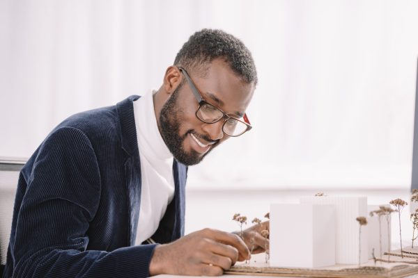 smiling bearded african american engineer working with business buildings model